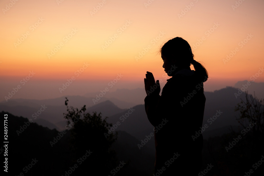 Silhouette of girl praying over beautiful sky background. Christian Religion concept background. fighting and victory for god