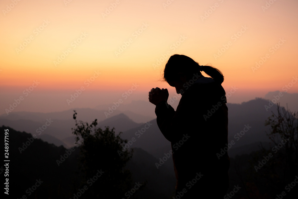 Silhouette of girl praying over beautiful sky background. Christian Religion concept background. fighting and victory for god