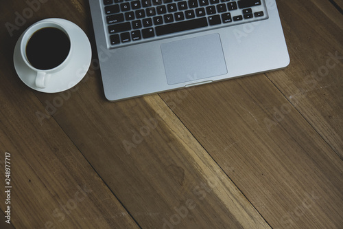 Top view table office with notebook, laptop, mobile, coffee cup, and pen with copy space on wooden table. Business concept.