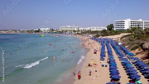 Aerial view of a holiday resort sandy beach, with beach umbrellas and sun beds. Crowded sandy beach in Ayia Napa Cyprus. photo