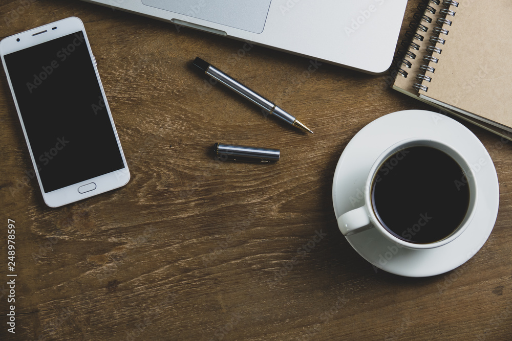 Top view table office with notebook, laptop, mobile, coffee cup, and pen with copy space on wooden table. Business concept. Top view table office with notebook, laptop, mobile, coffee cup, and pen with copy space on wooden table. Business concept.