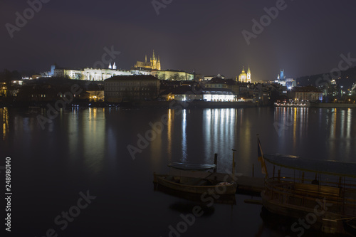 Vltava river, boats and Prague castle after dark