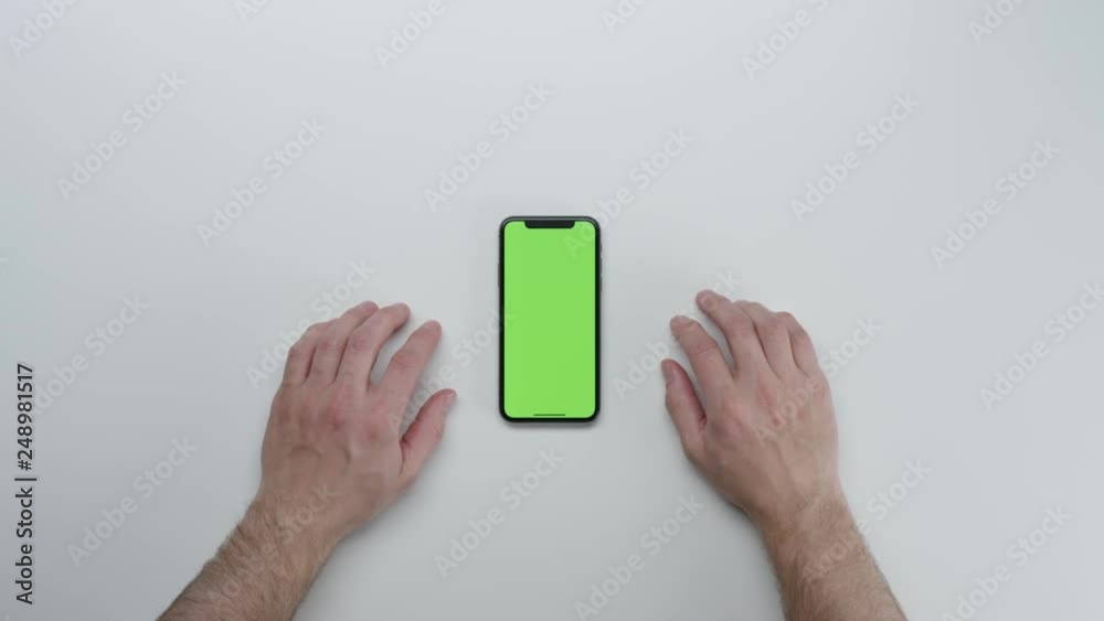 Male hands using smart device with green screen chroma on white clean minimalistic table with top view Male hands using smart device with green screen chroma on white clean minimalistic table with top view