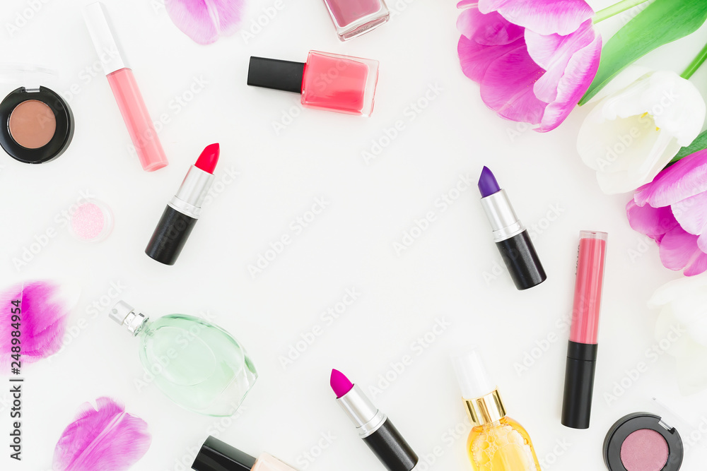 Frame made of tulips flowers and cosmetics, lipstick with nail polish on white background. Top view. Flat lay Frame made of tulips flowers and cosmetics, lipstick with nail polish on white background. Top view. Flat lay