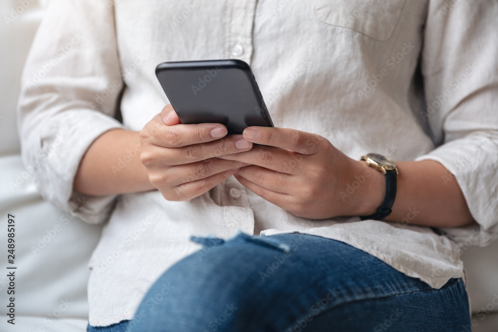 Closeup image of a woman holding , using and looking at smart phone in cafe Closeup image of a woman holding , using and looking at smart phone in cafe