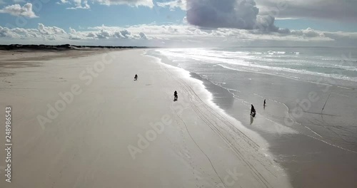 Stunning view of a white sandy beach with dark clouds over the ocean DRONE left tracking photo