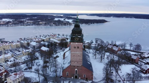 Drone footage while moving away from the old cathedral of Str√§ngn√§s revealing the old town. A frozen lake is in the background. Filmed in realtime at 4k. photo
