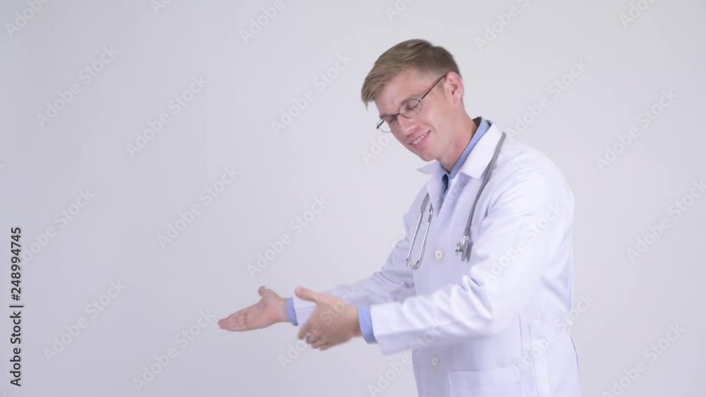 Happy young handsome man doctor showing something Happy young handsome man doctor showing something