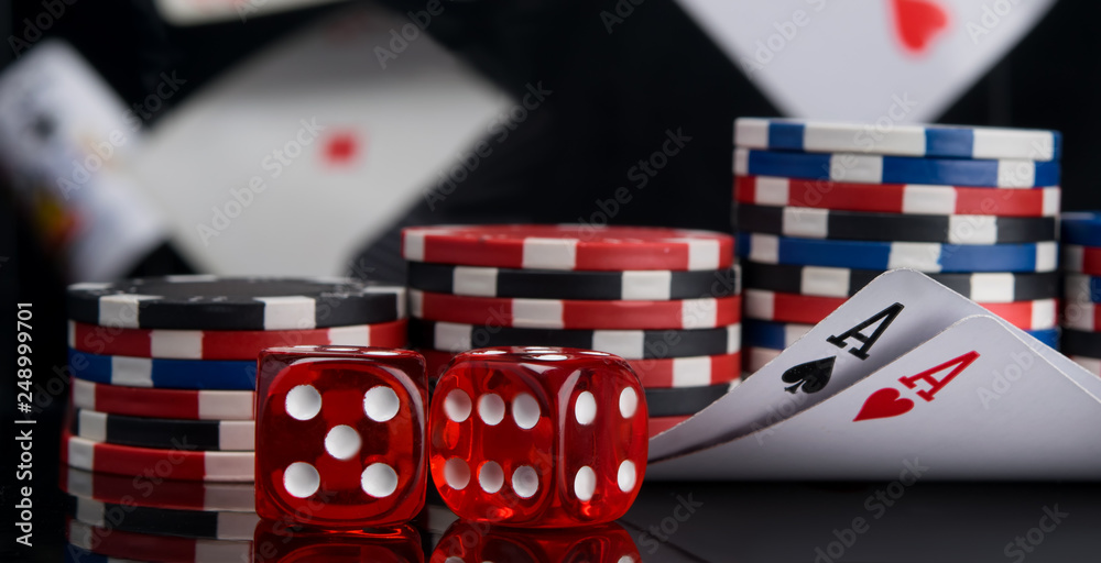 Obraz premium against the background of flying cards, two red dice and chips for betting in the casino, on the black table, with reflection
