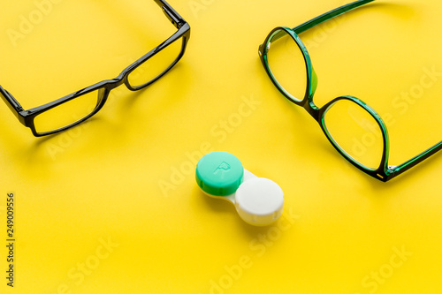 Eye problems. Glasses with transparent lenses and contact lenses on yellow background copy space