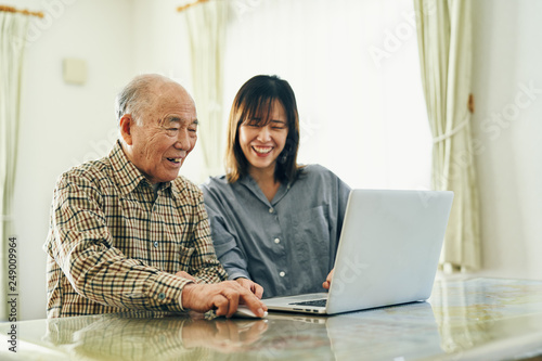 Grandfather and granddaughter using laptop at home