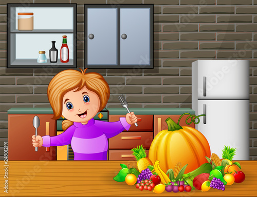 Happy little girl holding spoon and fork eating at the table