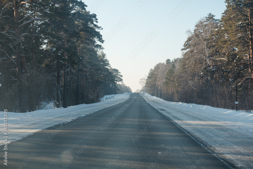 Asphalt road in winter in the forest. Asphalt under the snow. Road in the snow. Winter road. Asphalt road in winter in the forest. Asphalt under the snow. Road in the snow. Winter road.