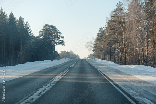 Asphalt road in winter in the forest. Asphalt under the snow. Road in the snow. Winter road.
