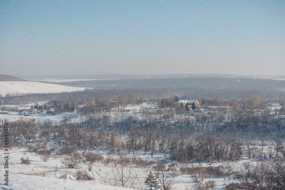 Obraz premium Winter view of the village from above. Houses in the snow. Countryside under the snow.
