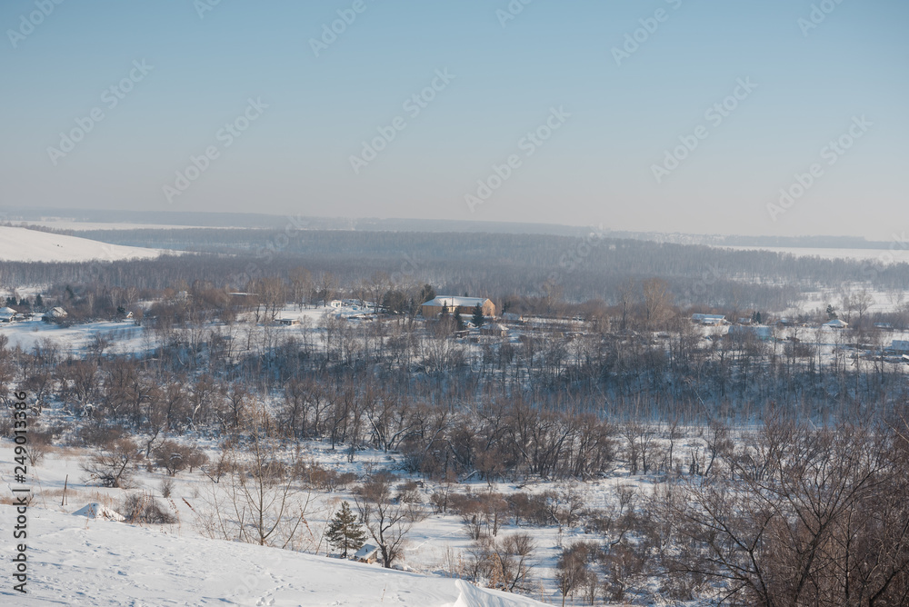 Fototapeta premium Winter view of the village from above. Houses in the snow. Countryside under the snow.