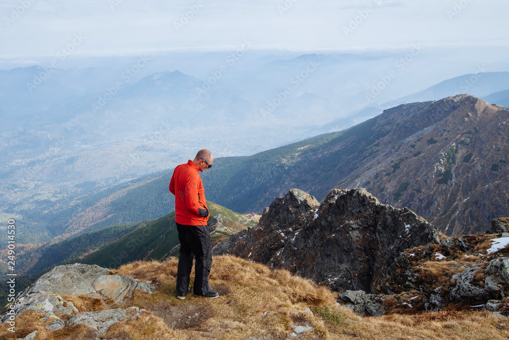 The young man of sporting physique rises to the mountain with sporting equipment