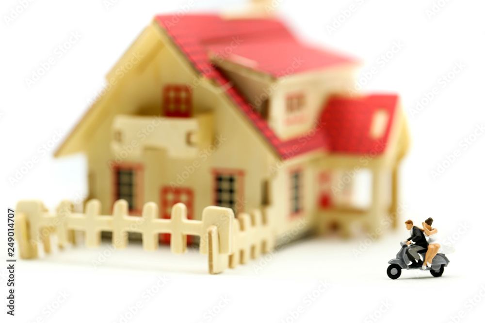 Fototapeta premium Miniature people : couple of love riding the motorcycle in front of their new home after buying real estate.