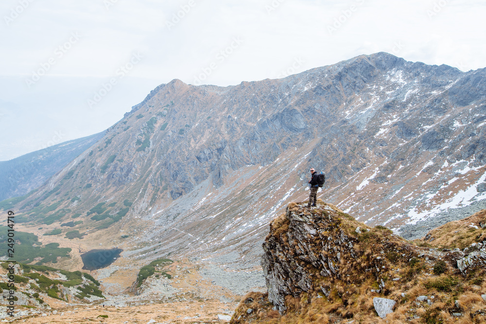 The young man of sporting physique rises to the mountain with sporting equipment