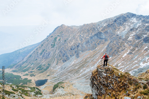 A young man sports athletes sitting on top of a mountain with sporting gear