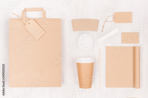 Eco friendly coffee template for design, advertising and branding - brown paper cup and blank bag, notebook, label, card, cap, sugar on white wood board, top view.