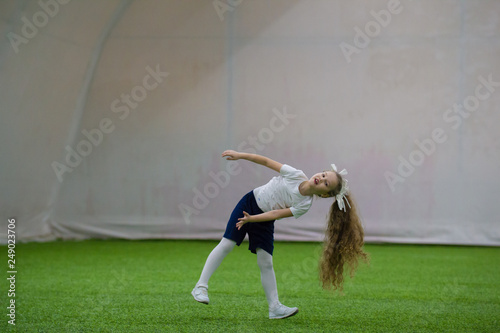 A cute little girl with long hair is tumbling on the field and laughing photo