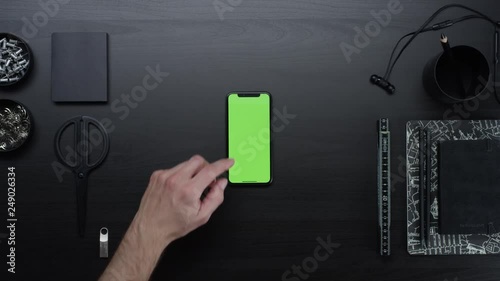 Male hands using smart device with green screen chroma on black clean minimalistic table with top view