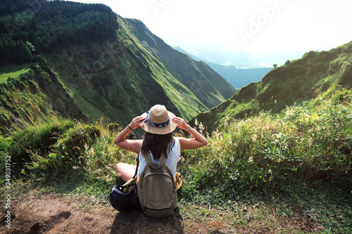 woman traveler holding hat and looking at amazing mountains and forest, wanderlust travel concept, space for text, atmospheric epic moment, azores ,portuhal, ponta delgada, sao miguel