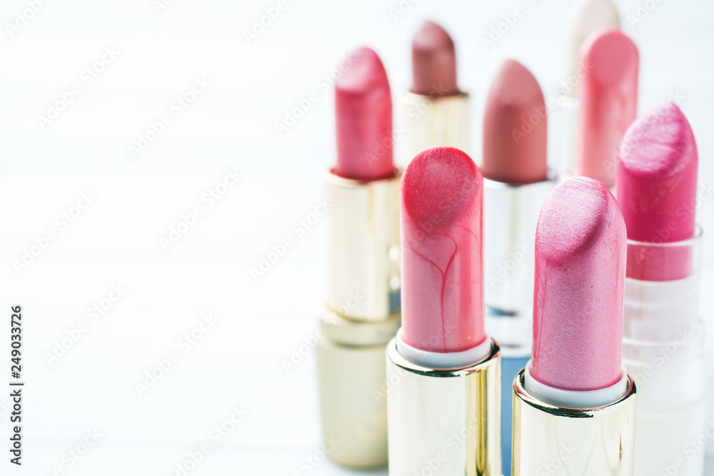Obraz premium Set of colored pink lipsticks on white background. Women's cosmetics. Selective focus. Copy space.