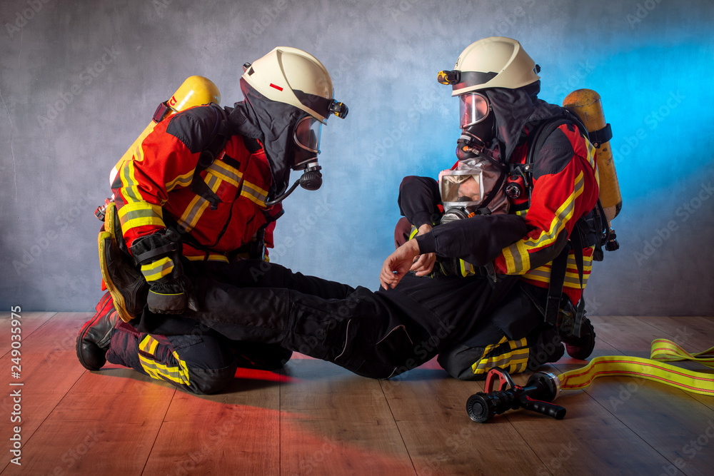 Fototapeta premium Feuerwehr, Atemschutztrupp im Einsatz, verletzte Person wird mit Rettungsgriff aus dem Gefahrenbereich gebracht