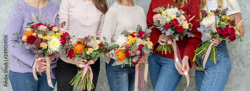 Florist workplace. Woman arranging a bouquet with roses, chrysanthemum, carnation and other flowers. A teacher and students of floristry in master classes or courses