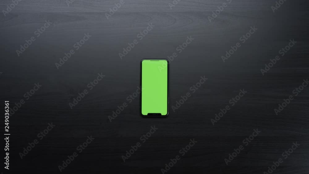 Male hands using smart device with green screen chroma on black clean minimalistic table with top view Male hands using smart device with green screen chroma on black clean minimalistic table with top view