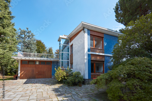 Villa with garden and garage in a sunny summer day, clear blue sky