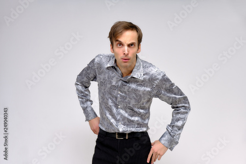Concept studio portrait of a handsome young man isolated on a white background with different emotions in a silver-colored shirt. © Вячеслав Чичаев