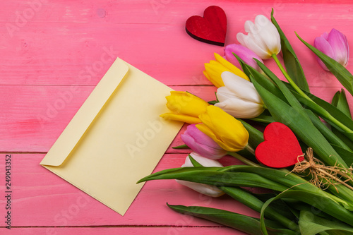 Fototapeta Naklejka Na Ścianę i Meble -  Fresh tulips, red hearts and blank envelope on wooden pink background 