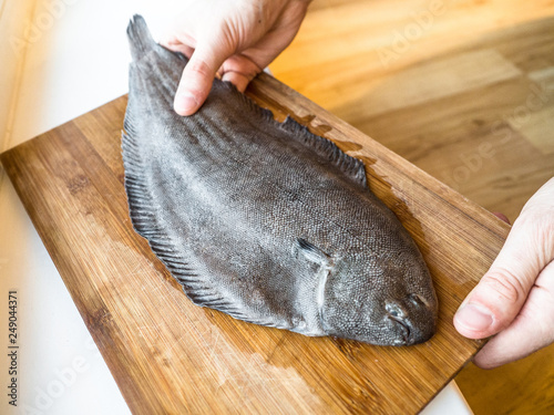 Fresh halibut in the kitchen, preparing for food, cooking with knife.
