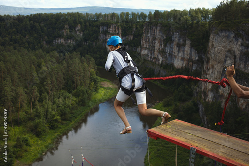 Woman-ropejumper jumps from a great height against the background of a rocky canyon and a river. Jump with a rope.