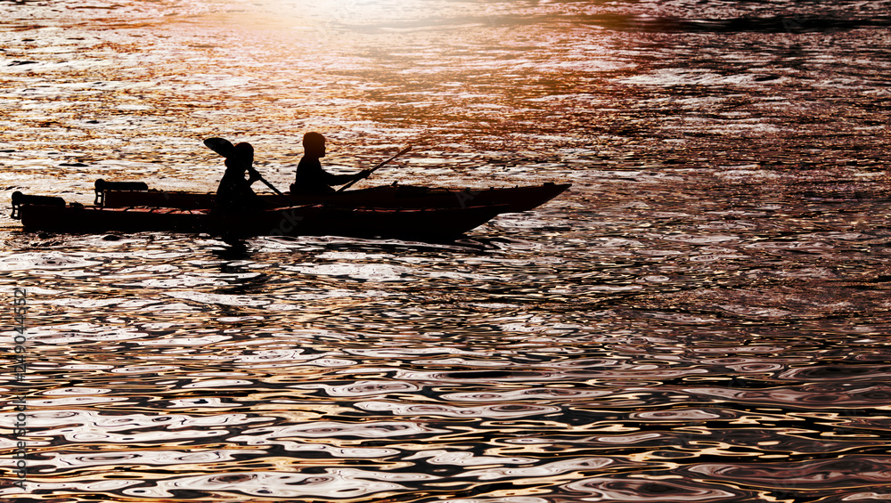 Silhouette of Two persons kayaking in the sea at sunset