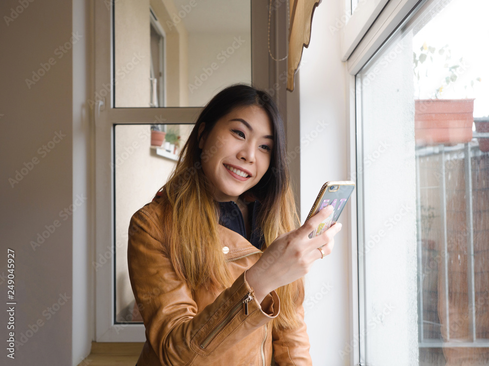 Hipster young Asian woman freelancer using the technology smart phone mobile video call and smile with her family, friends at home.