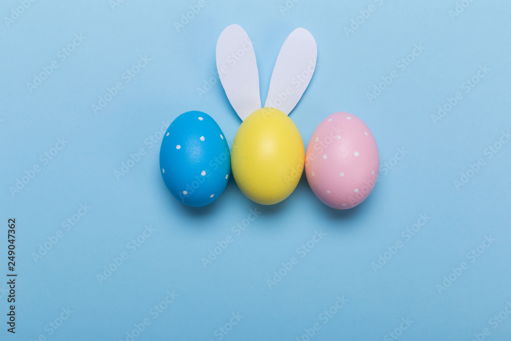 Colorfull easter eggs in nest on blue pastel color background with space.