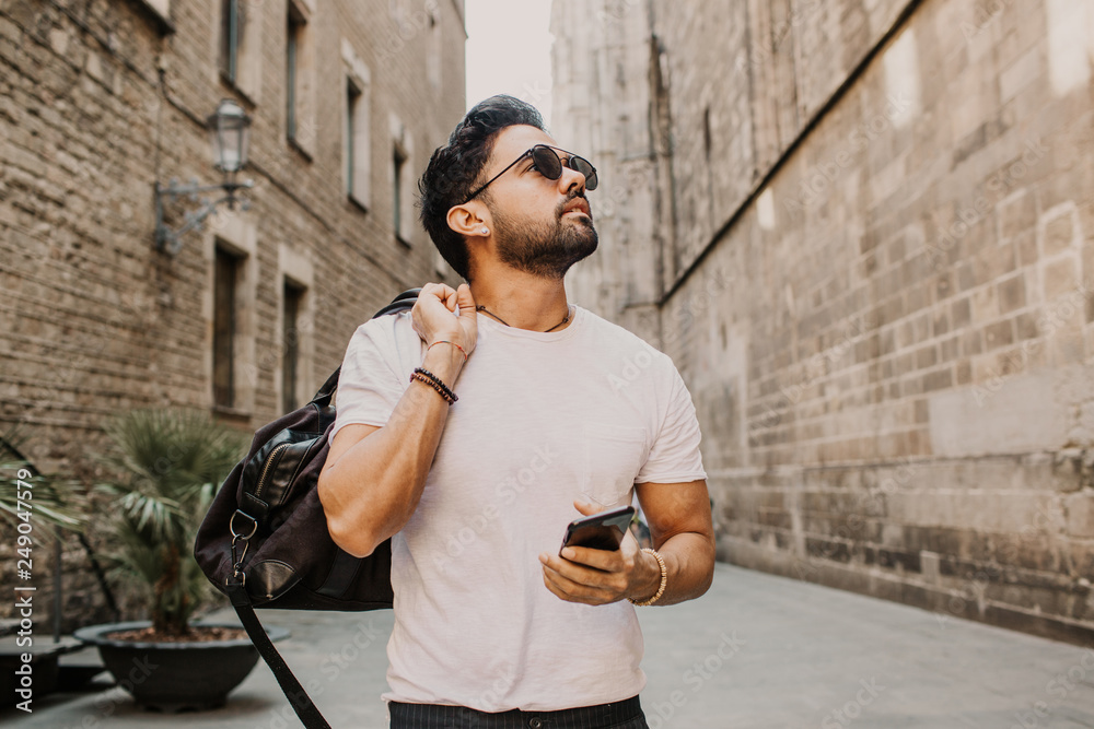 Young urban professional man using smart phone. Hipster coworker holding mobile smartphone using app texting sms message wearing sunglasses. Young urban professional man using smart phone. Hipster coworker holding mobile smartphone using app texting sms message wearing sunglasses.