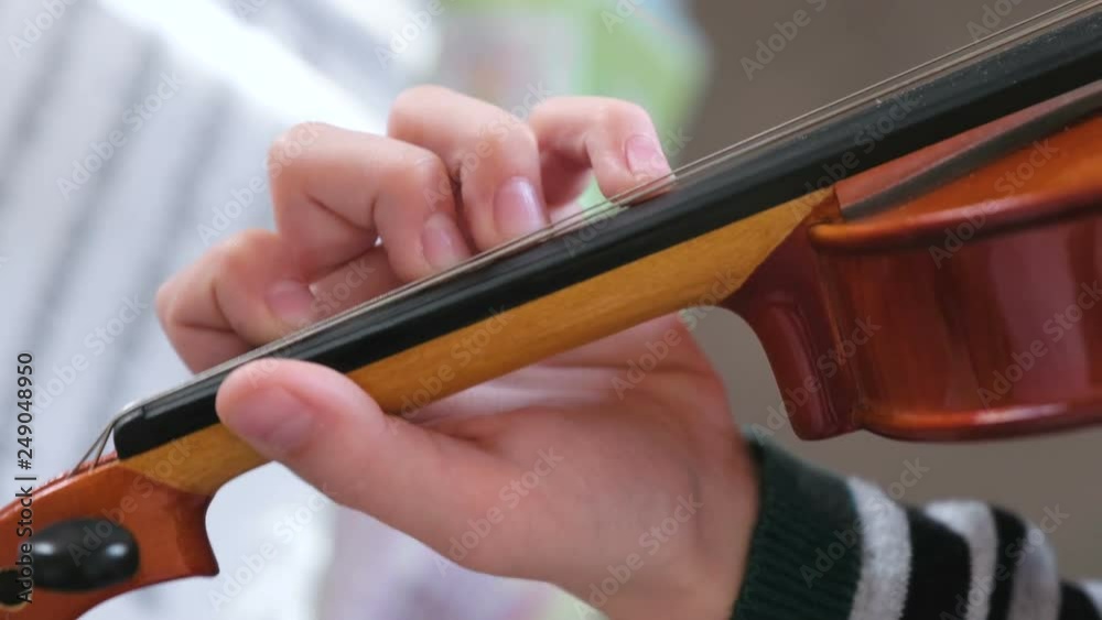 Violin in boy's hands. Boy is learning to play violin. Correct setting of the fingers of the left hand on the strings of the violin. Violin in boy's hands. Boy is learning to play violin. Correct setting of the fingers of the left hand on the strings of the violin.