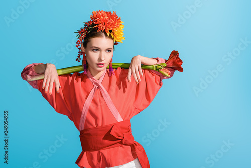 beautiful elegant girl in wreath holding living coral flower isolated on blue. Pantone color of the year 2019 concept