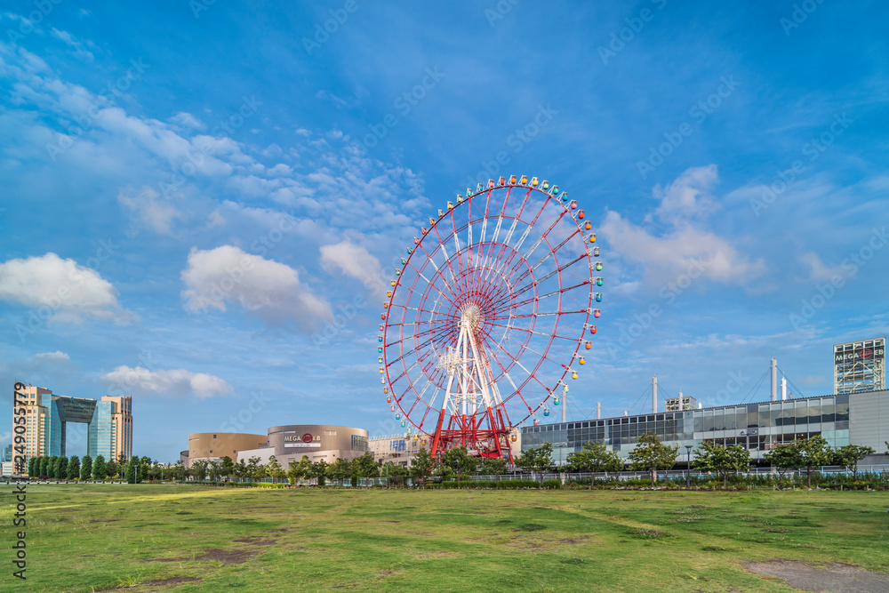 Odaiba colorful tall Palette Town Ferris wheel named Daikanransha visible from the central urban area of Tokyo in the summer blue sky. Passengers can see the Tokyo Tower.