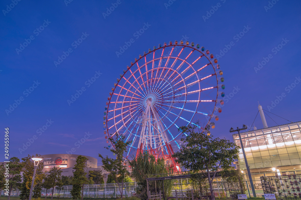 Fototapeta premium Odaiba illuminated Palette Town Ferris wheel named Daikanransha visible from the central urban area of Tokyo in the summer night sky. Passengers can see the Tokyo Tower.