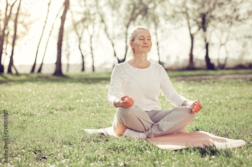 Relaxed mature woman doing yoga in park