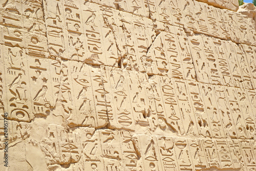 Egyptian hieroglyphs, symbols and signs on a stone wall in Karnak temple. Elements and details of bass-relief.