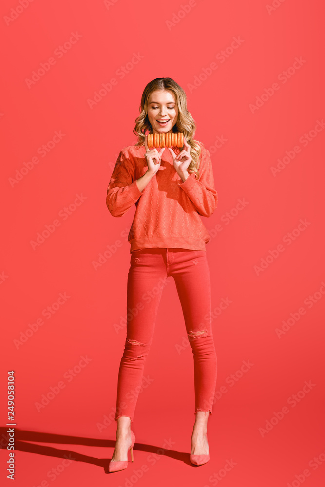 happy woman holding macaroons on living coral.  color of the year 2019 concept