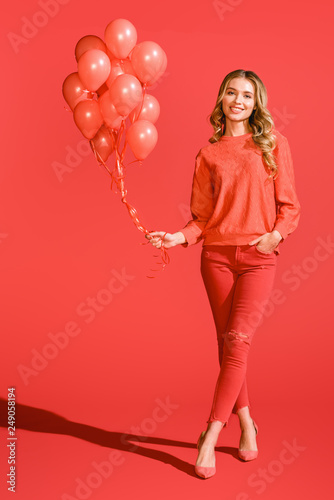 cheerful fashionable girl posing with living coral balloons. color of the year 2019 concept