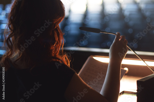 Woman is making a speech with microphone in a empty lecture hall